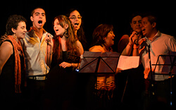 Fotografía de varias personas cantando en vivo.