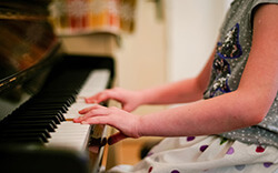 Fotografía de las manos de una niña tocando un piano.